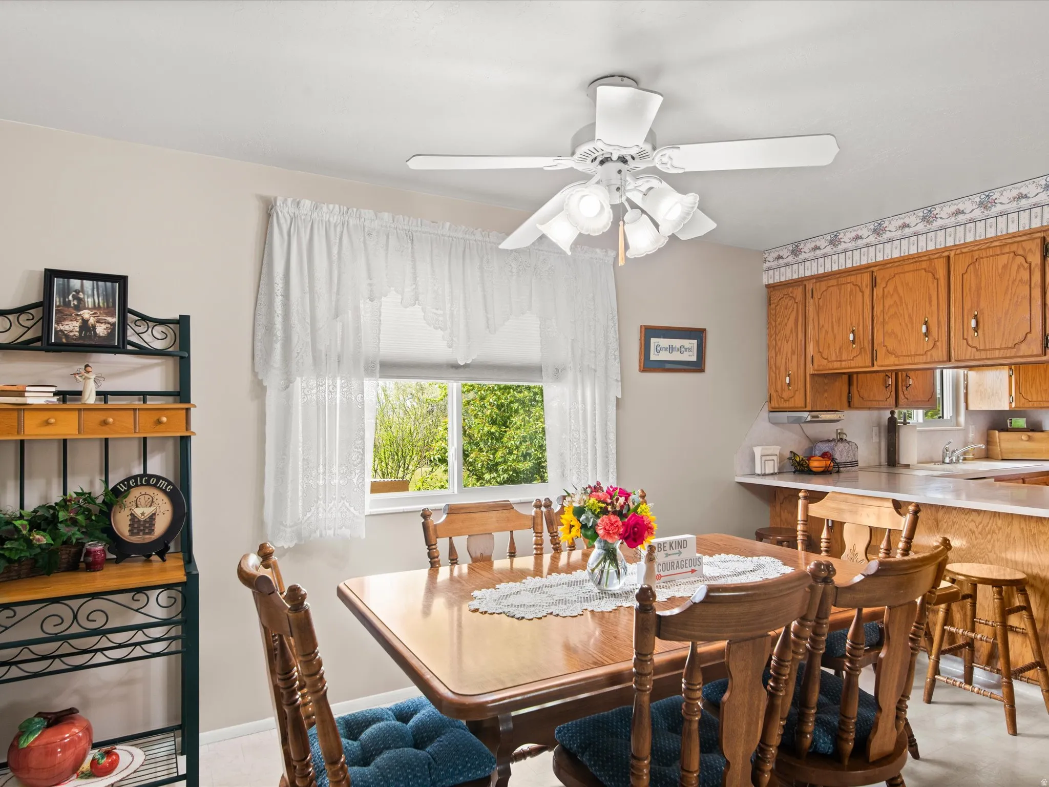 Dining area featuring a ceiling fan with integrated lighting, wood-finish dining table, and a window providing natural light