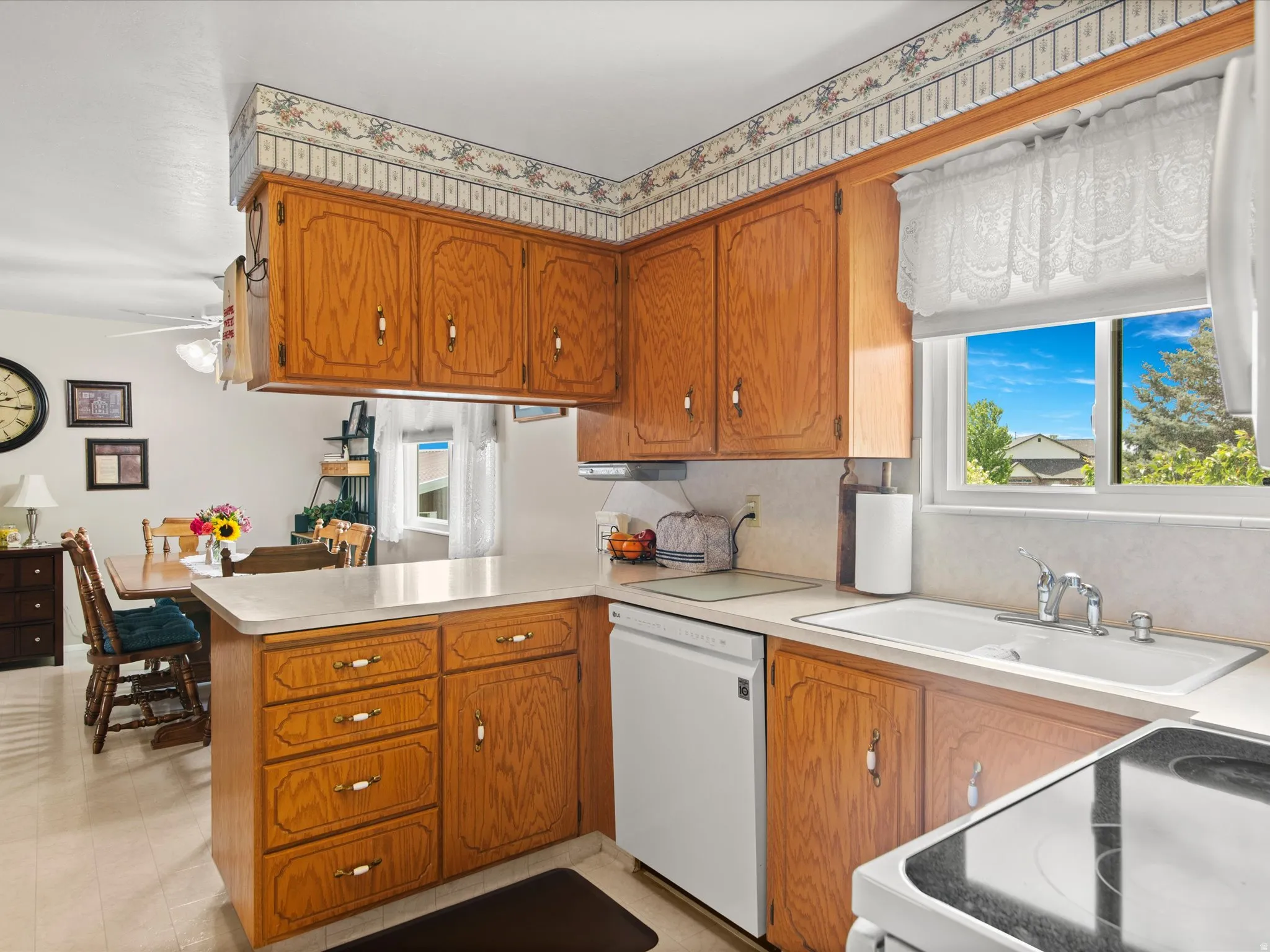 Kitchen featuring wood cabinetry, light countertops, and a white sink with a chrome faucet