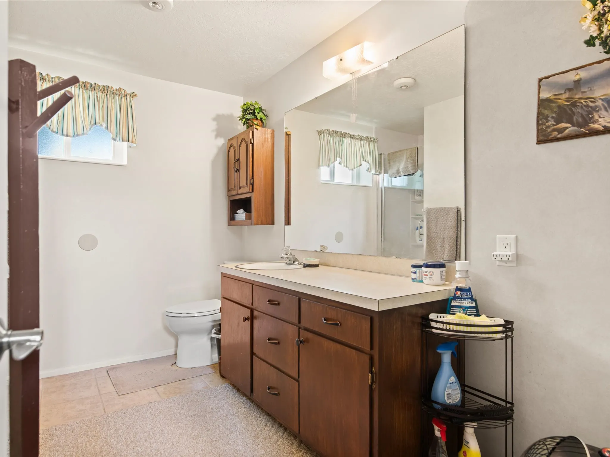 Bathroom vanity featuring a laminate countertop, integrated sink, and wood-finish cabinetry