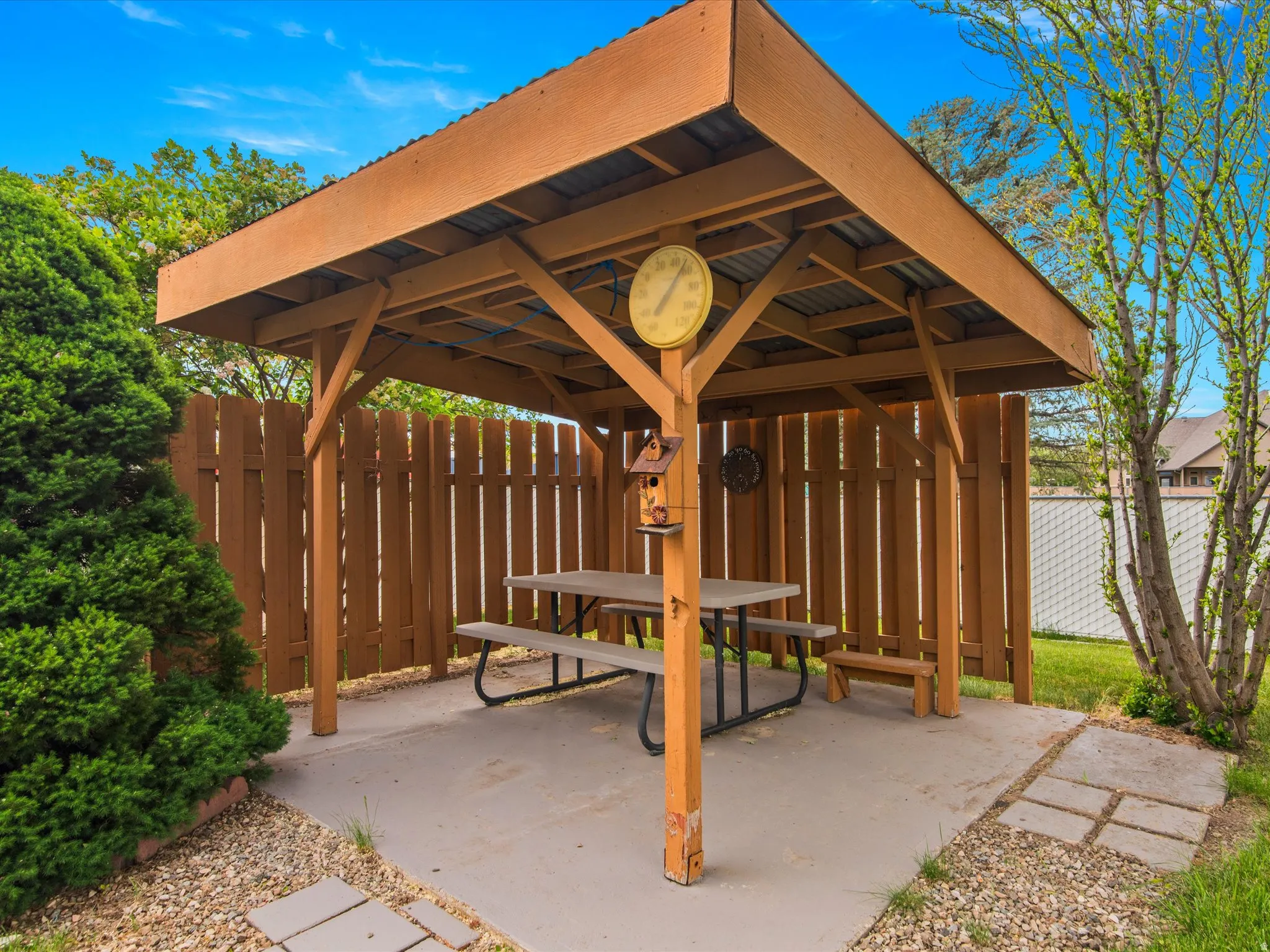 Wood-frame gazebo with a corrugated metal roof over a concrete patio