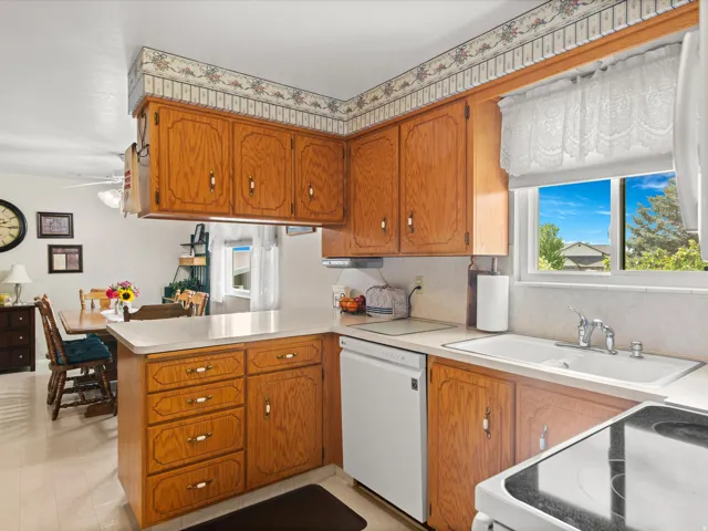 Kitchen featuring wood cabinetry, light countertops, and a white sink with a chrome faucet