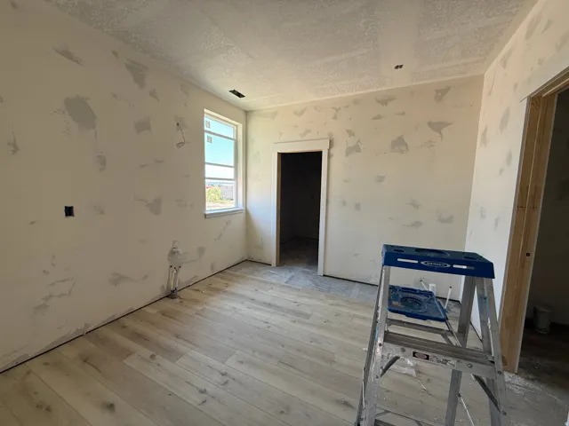 Wood-finish flooring with a light tone, multiple window openings, and an unfinished ceiling