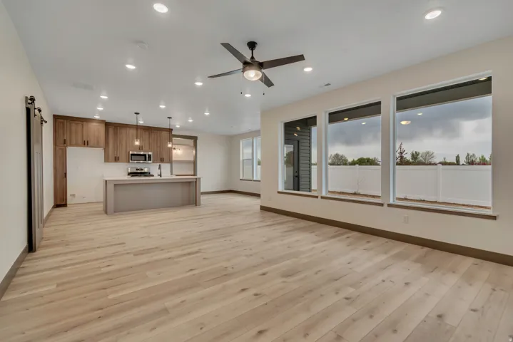 Kitchen with open floor plan, an island with sink, light countertops, light wood-style floors, and ceiling fan