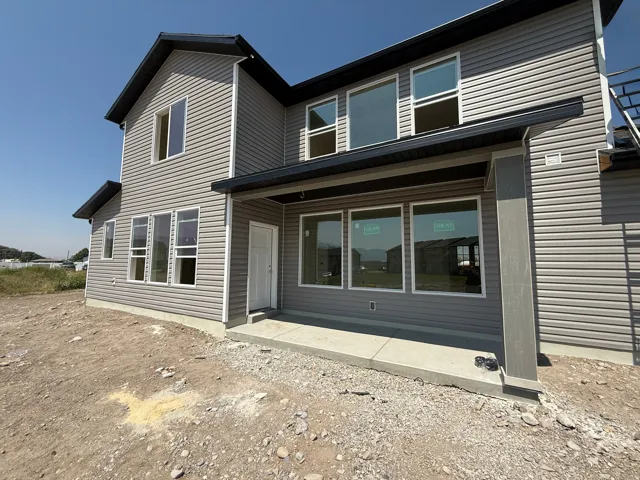 Gray horizontal siding exterior with a covered patio and multiple large windows