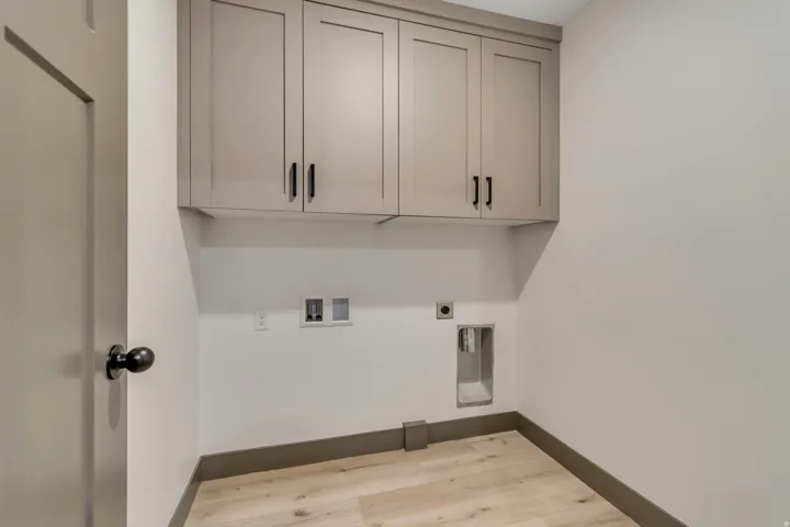 Laundry area with light wood-type flooring, hookup for a washing machine, cabinet space, and electric dryer hookup