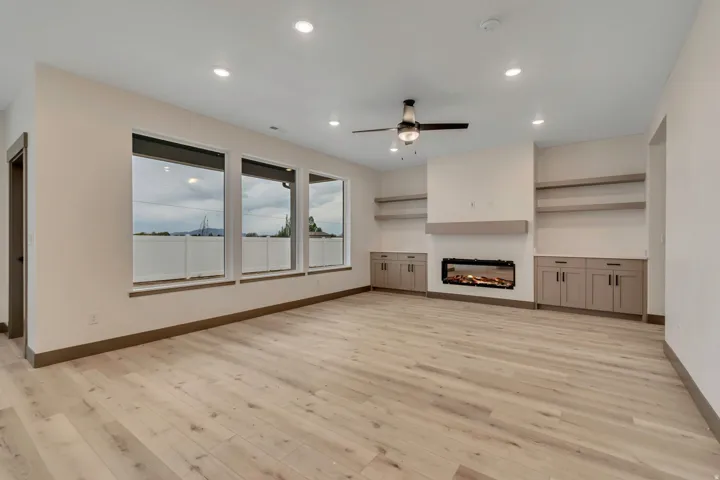 Unfurnished living room with ceiling fan, a glass covered fireplace, recessed lighting, and light wood-type flooring