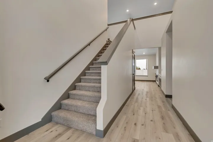 Staircase with wood finished floors and recessed lighting