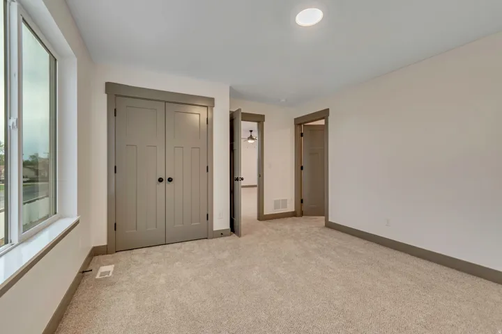 Unfurnished bedroom with light carpet and a closet