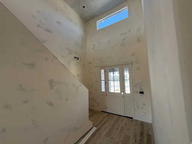 Double entry doors with glass panels, wood-finish flooring, and a transom window above