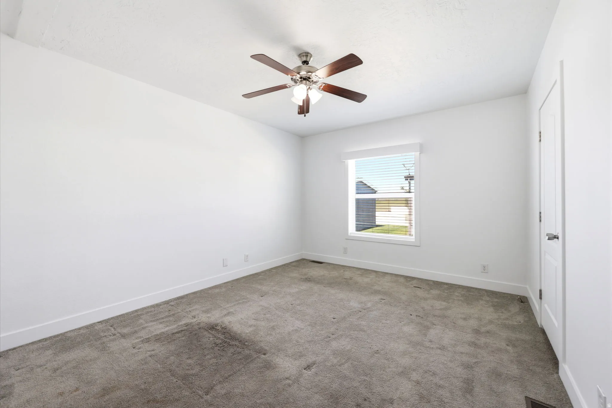 Carpeted room with a ceiling fan featuring wood-finish blades and integrated lighting