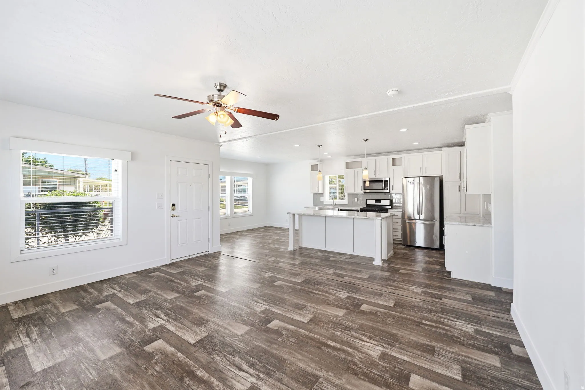 Open-concept living space featuring wood-finish flooring, white walls, and a ceiling fan