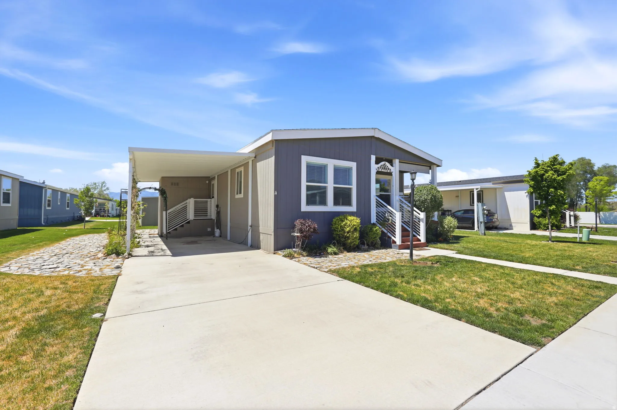 Single-story residence featuring a covered carport, concrete driveway, and a front porch with white railings