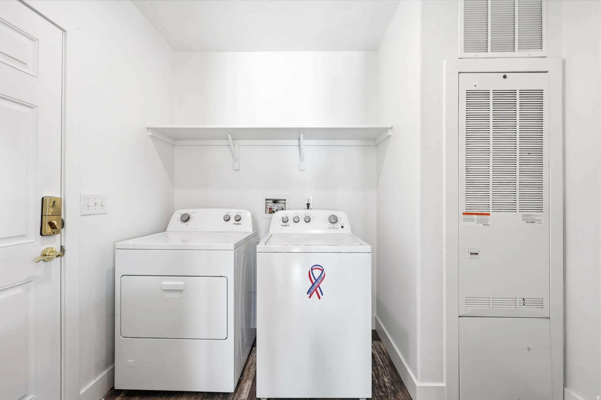 Dedicated laundry area featuring wood-finish flooring and a white wall shelf