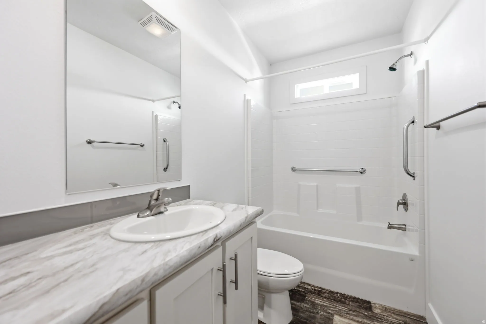 Bathroom featuring a single vanity with a white oval sink, a light-toned marbled countertop, and white shaker-style cabinetry