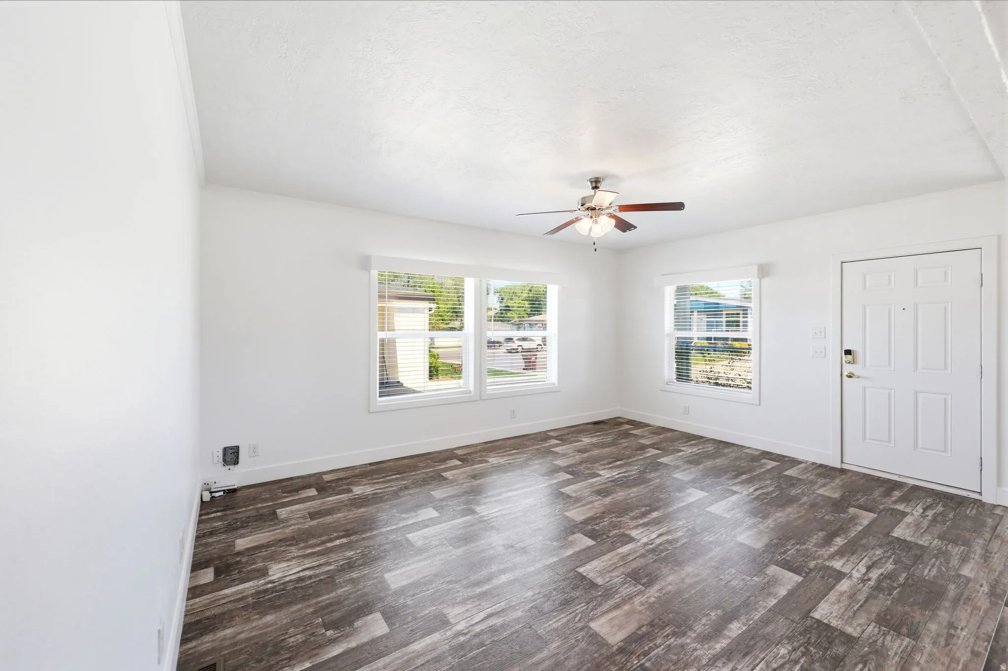 Bright living area featuring wood-finish flooring, white walls, and a ceiling fan