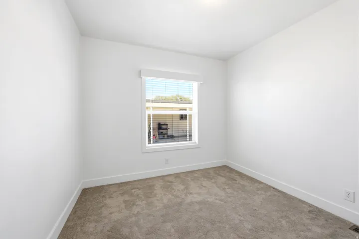 Neutral toned carpeted room featuring white walls and a single window with blinds