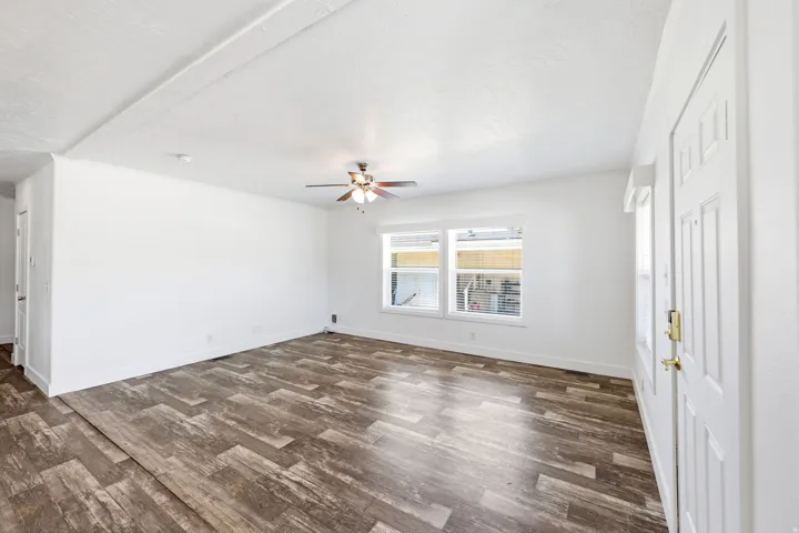 Open-concept living space featuring wood-finish flooring, white walls, and a ceiling fan