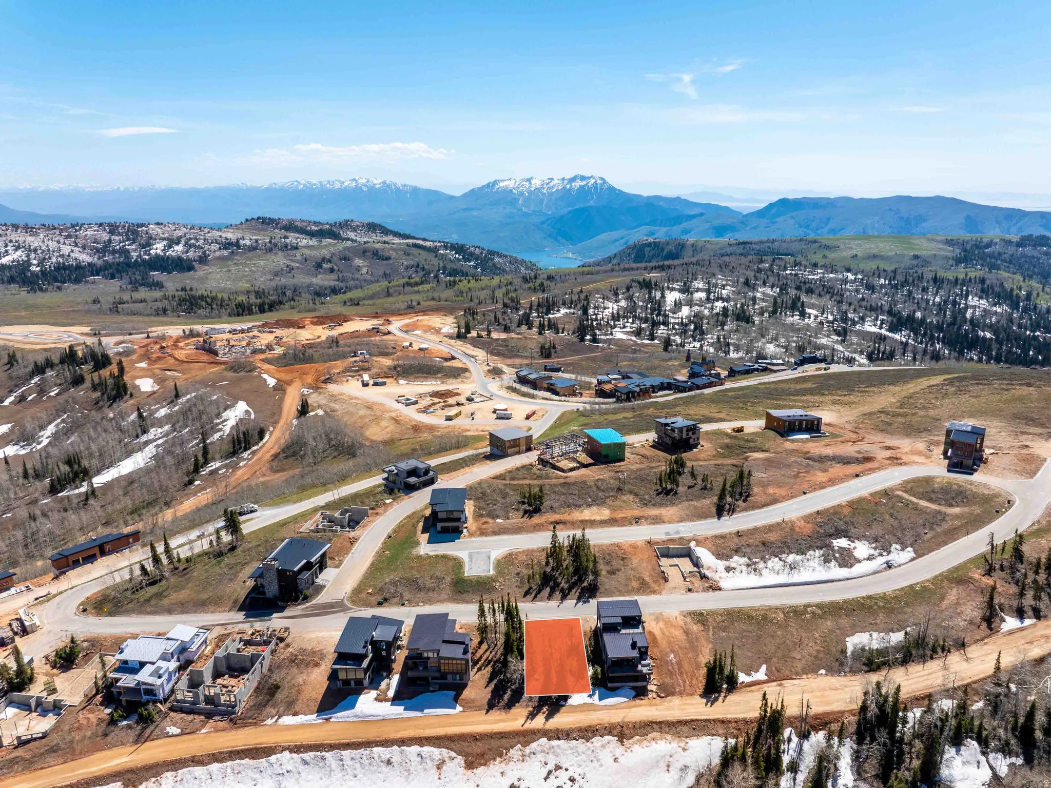 Aerial overview of a mountain community featuring multiple residential properties and building sites