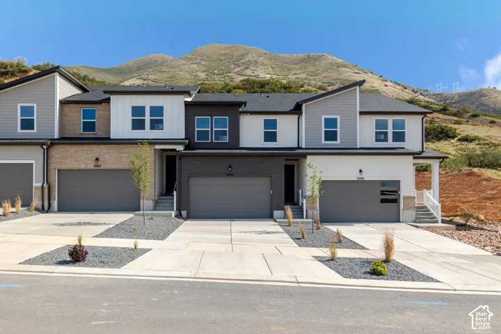Multi-unit exterior featuring mixed materials including brick veneer, stucco, and horizontal siding with an attached mountain backdrop