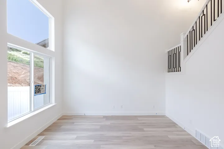 Double-height ceiling, wood-finish flooring, stacked window configuration, and staircase with metal balusters