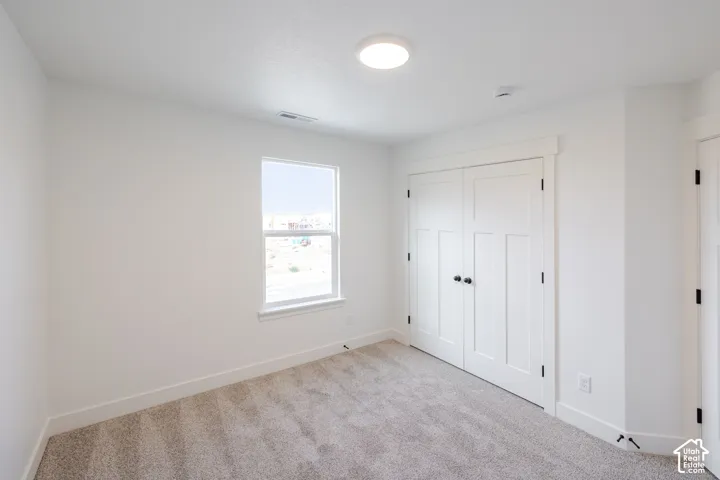 Neutral-toned carpeting, dual-panel interior doors, recessed ceiling lighting, and a single-pane window with white trim