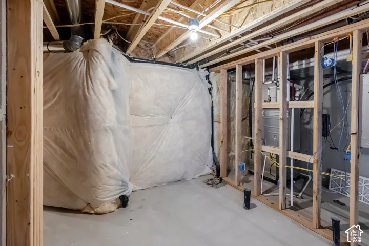 Unfinished space featuring exposed timber framing, concrete flooring, vapor barrier insulation, and exposed mechanical systems