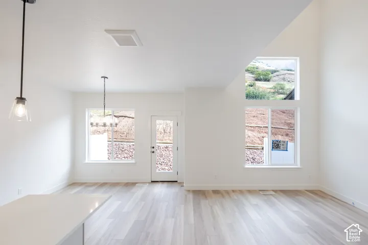 Vaulted ceilings, wood-finish flooring, multi-level windows, pendant lighting, and a neutral color palette