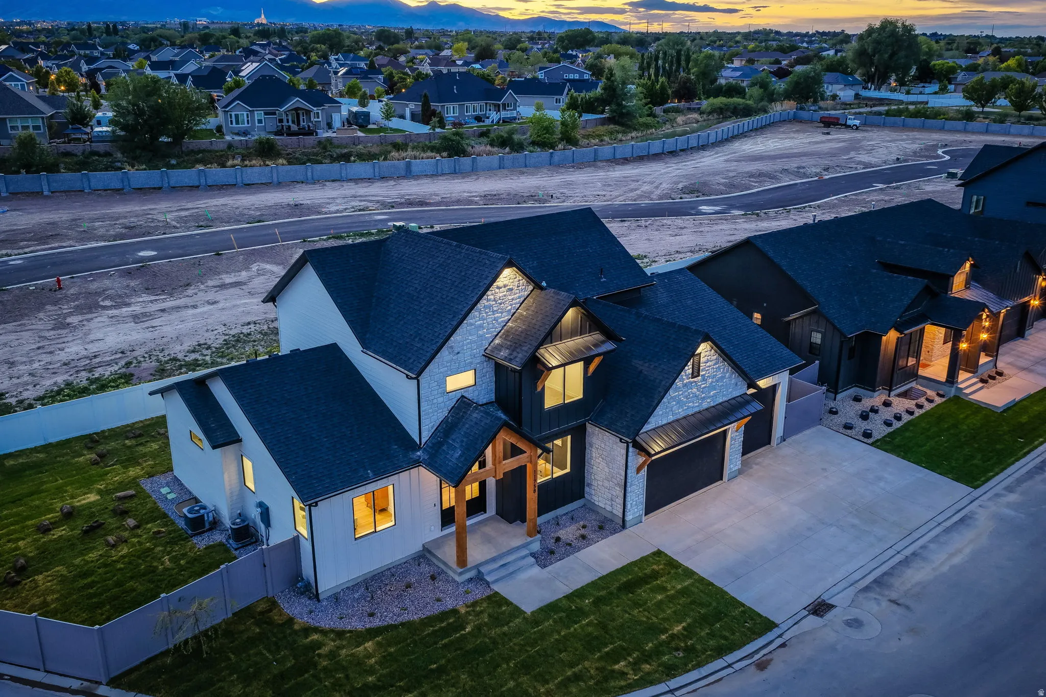 Contemporary residence featuring a striking black exterior with stone accents and a dual-car garage