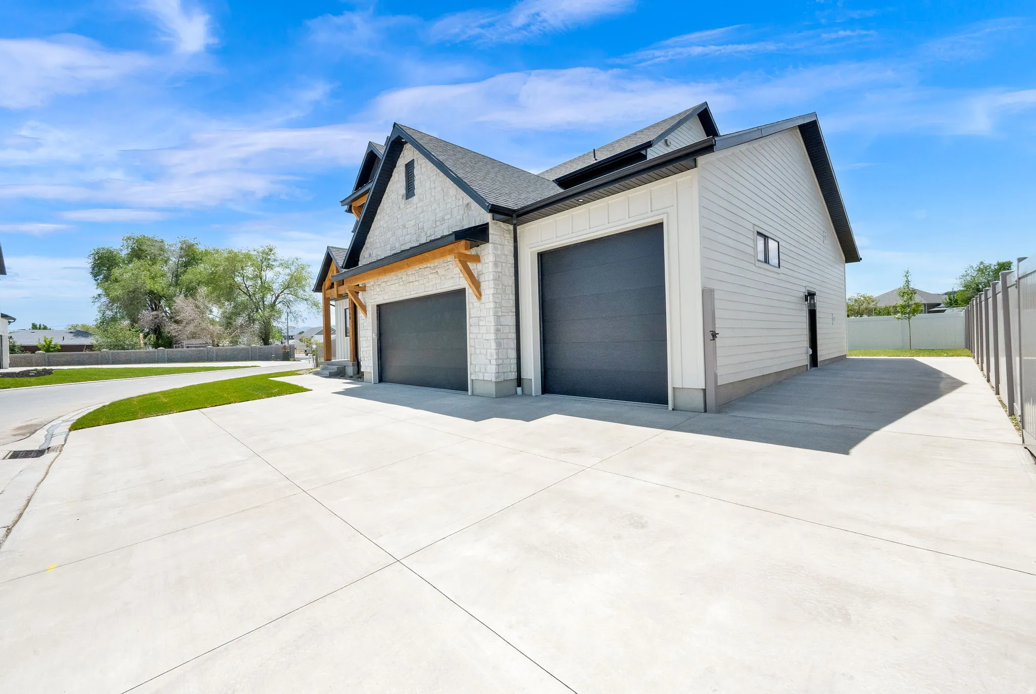 Contemporary exterior featuring light stone cladding, dark siding, and a prominent two-car garage with dark doors