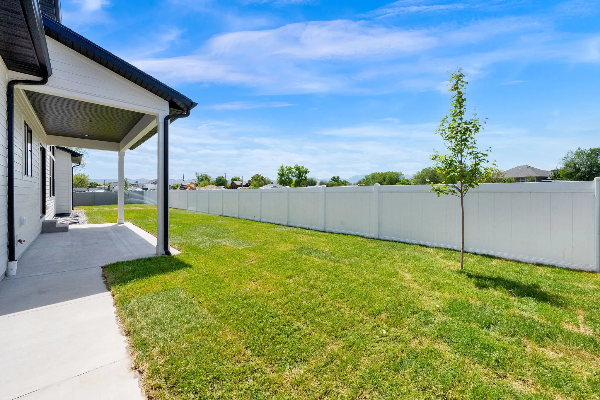 Expansive green lawn with a white privacy fence