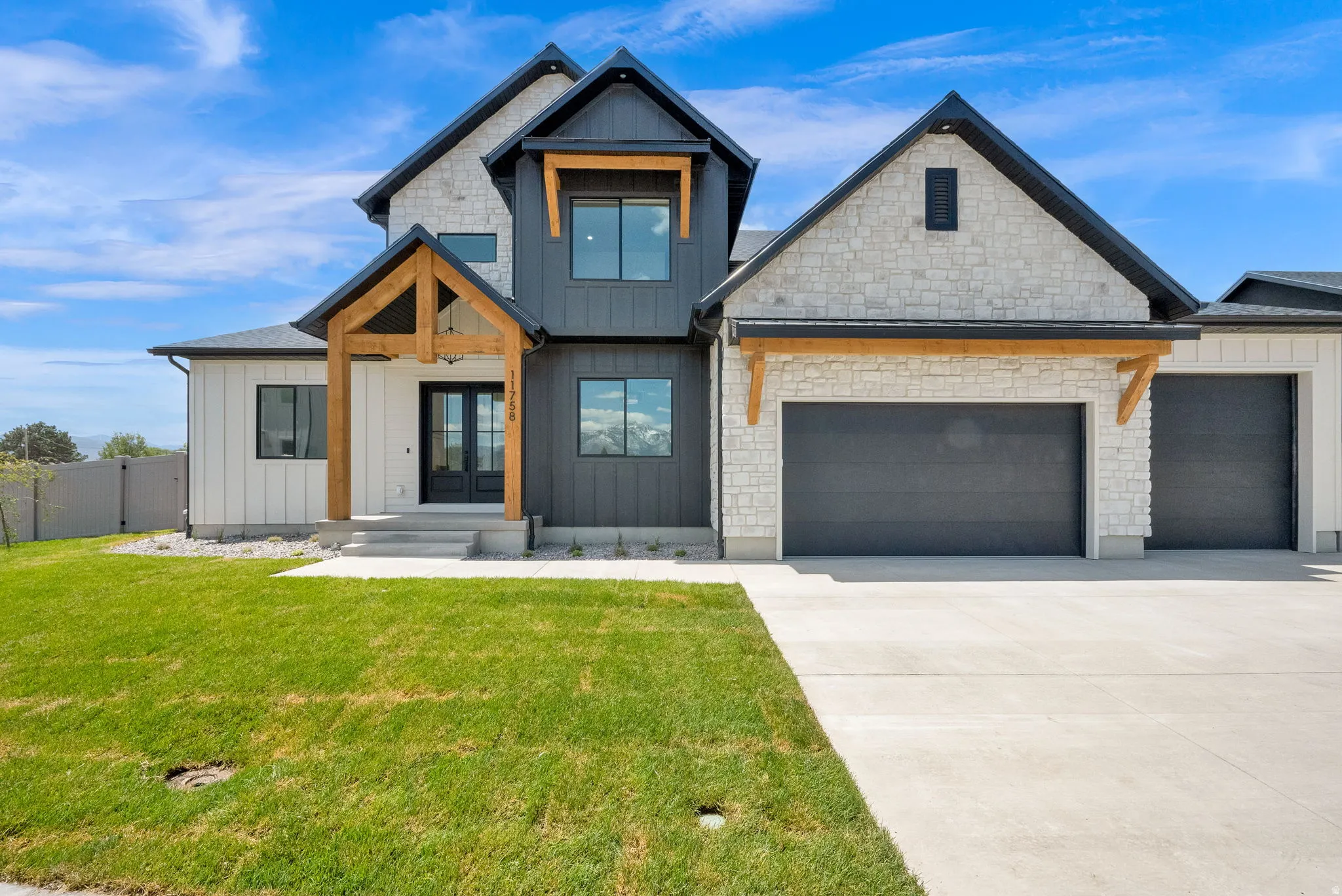 Modern farmhouse exterior featuring mixed materials including vertical white siding, dark vertical board and batten siding, and light-toned stone