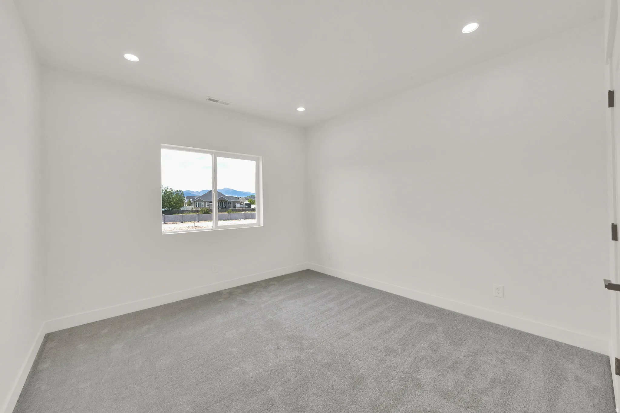 Spacious room featuring a large window, recessed lighting, and grey carpeting