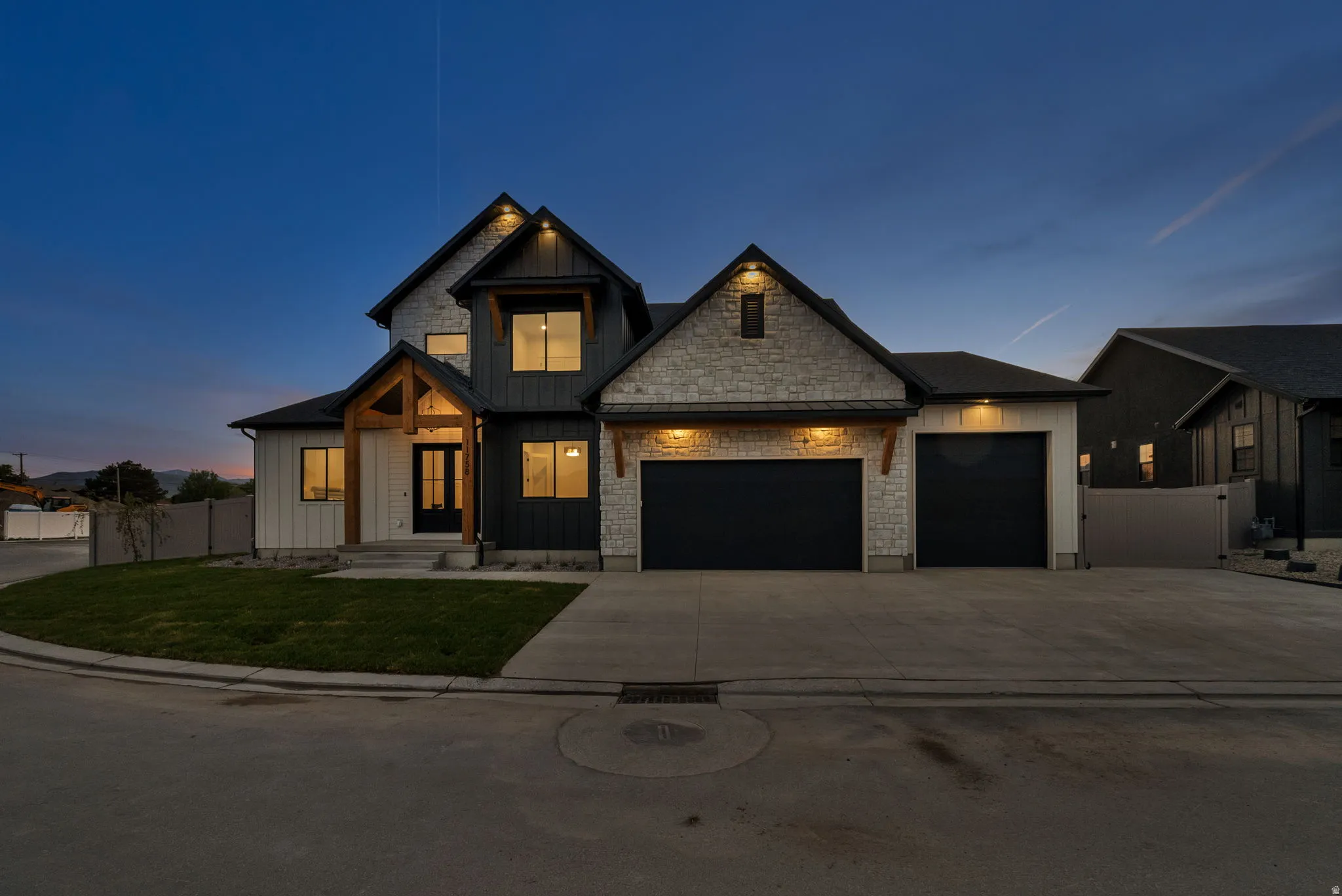 Modern farmhouse-style exterior featuring a striking combination of light stone veneer, vertical dark siding, and white board and batten