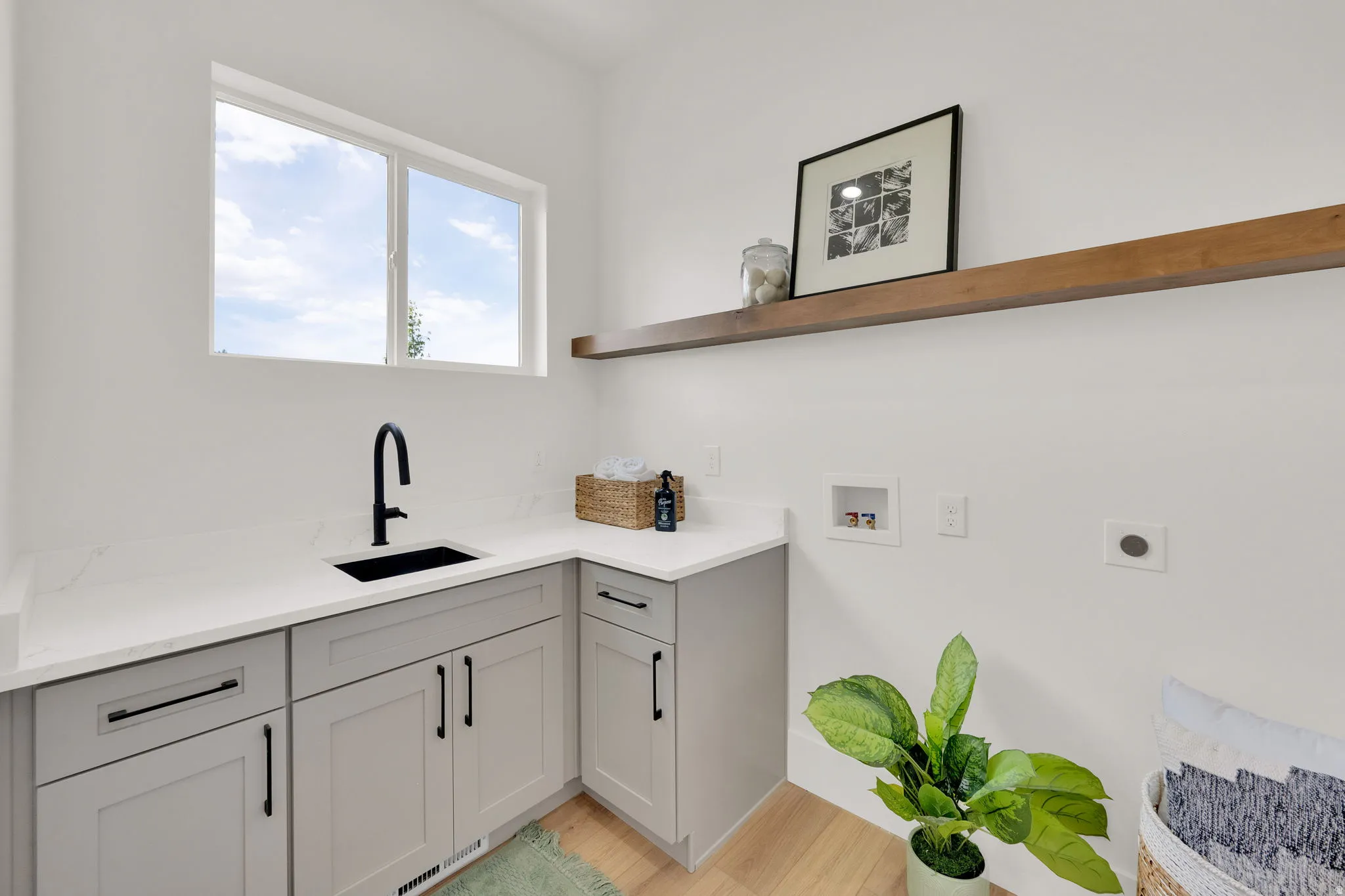 Laundry area featuring light gray cabinetry with black hardware, a black sink, and a black gooseneck faucet