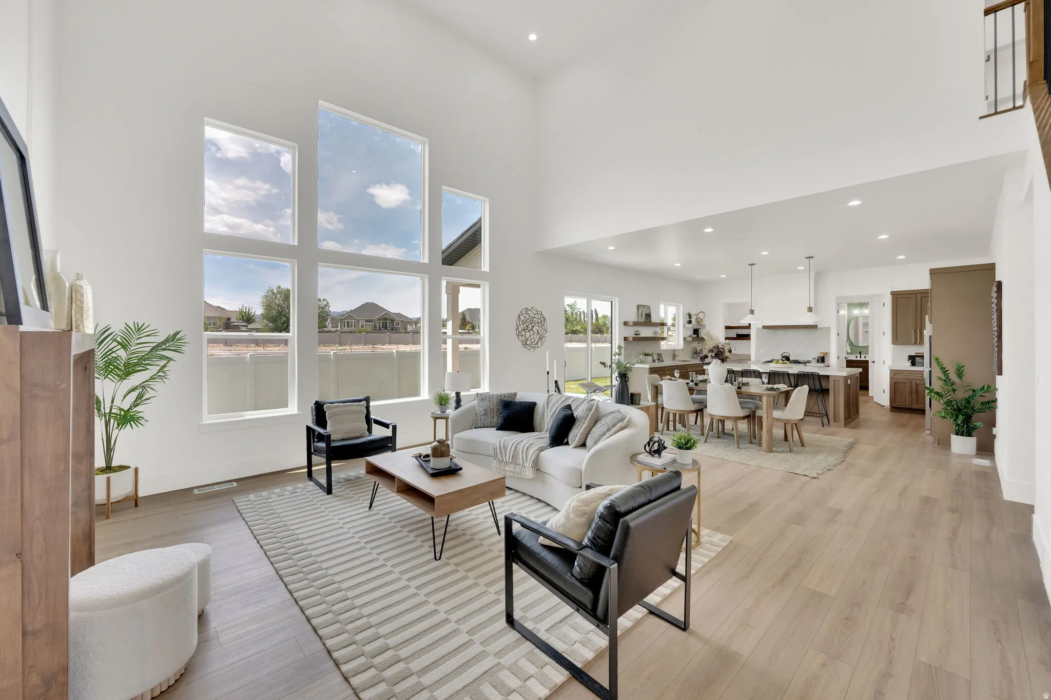 Spacious living area featuring a vaulted ceiling, floor-to-ceiling windows, and wood-finish flooring