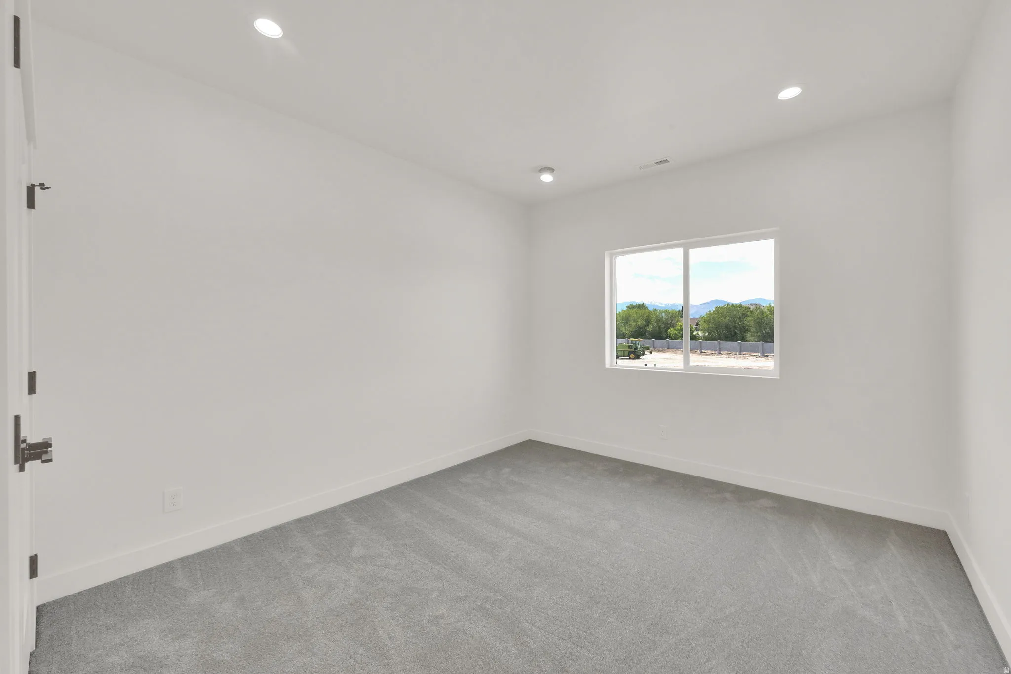 Bright room featuring a large window, recessed lighting, and soft gray carpeting
