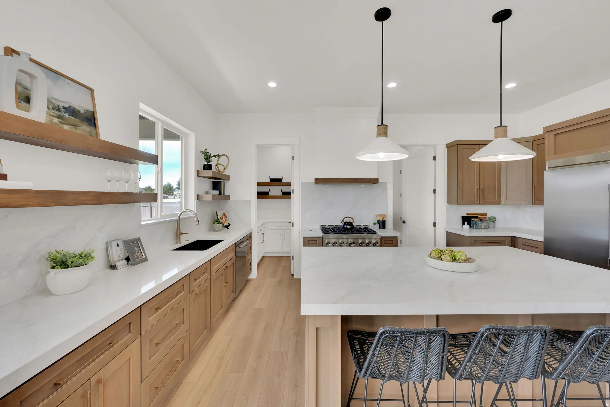 White kitchen featuring an island with pendant lighting, light wood-finish flooring, white countertops, and wood cabinetry