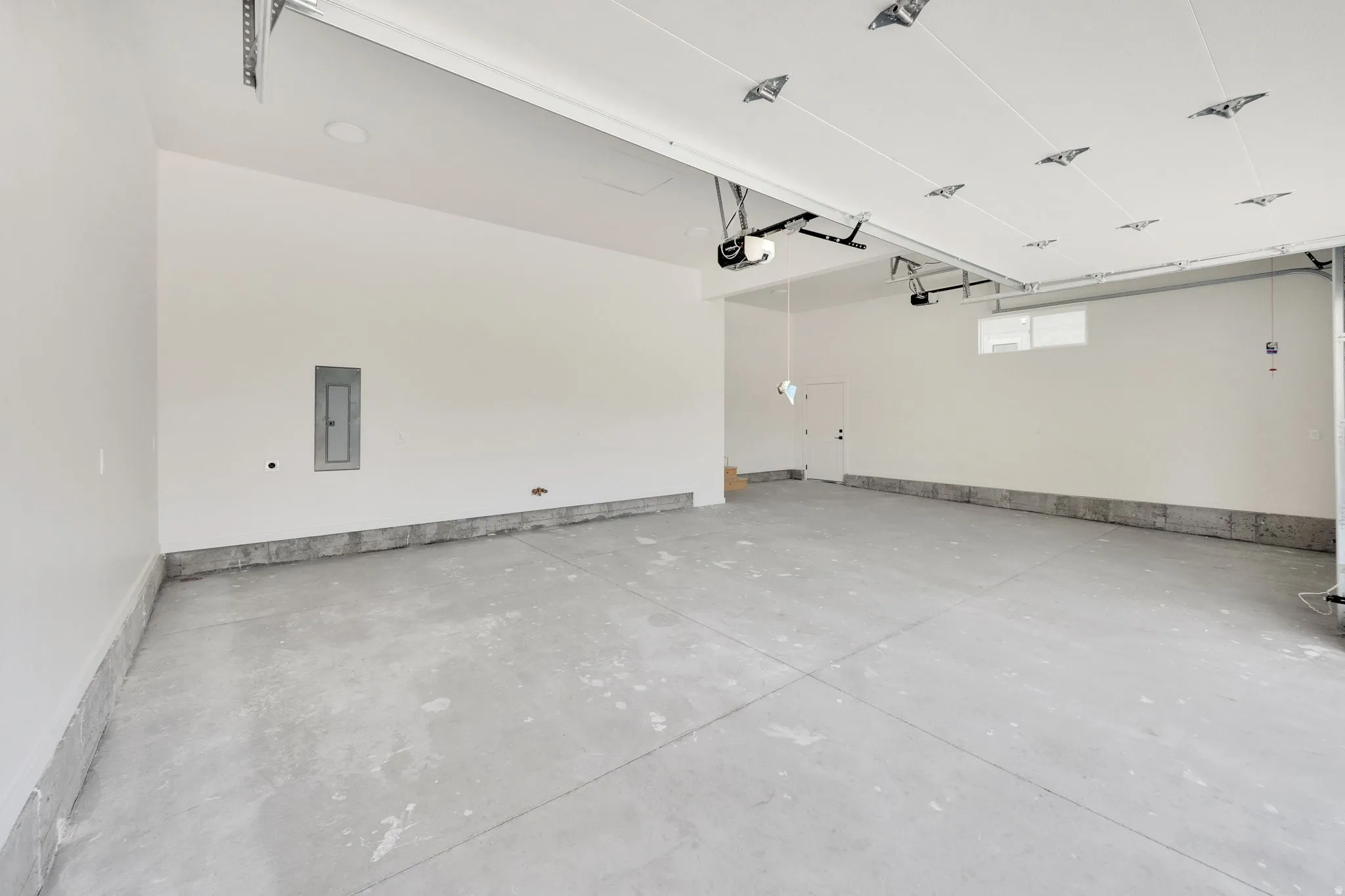 Spacious garage featuring a concrete floor, painted white walls, and an overhead door mechanism