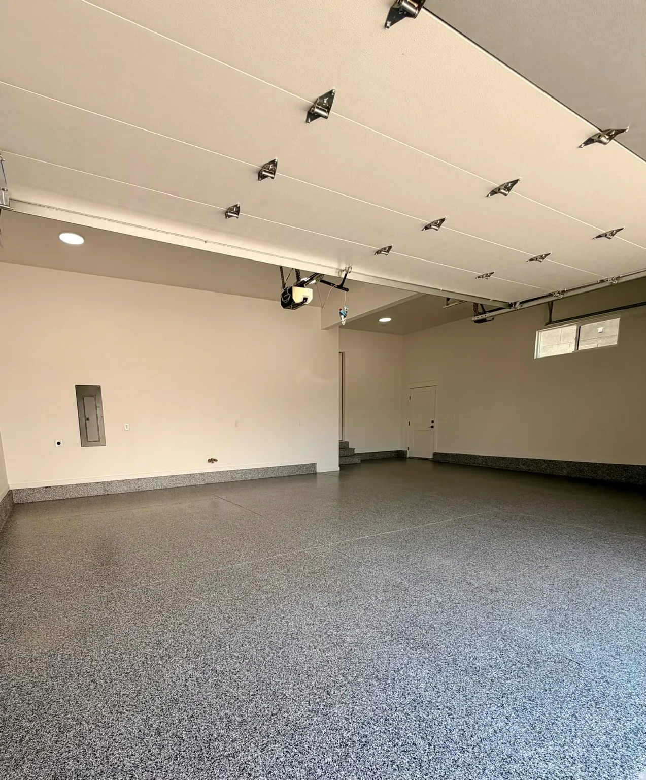 Spacious garage featuring a durable epoxy floor, recessed lighting, and a window for natural light