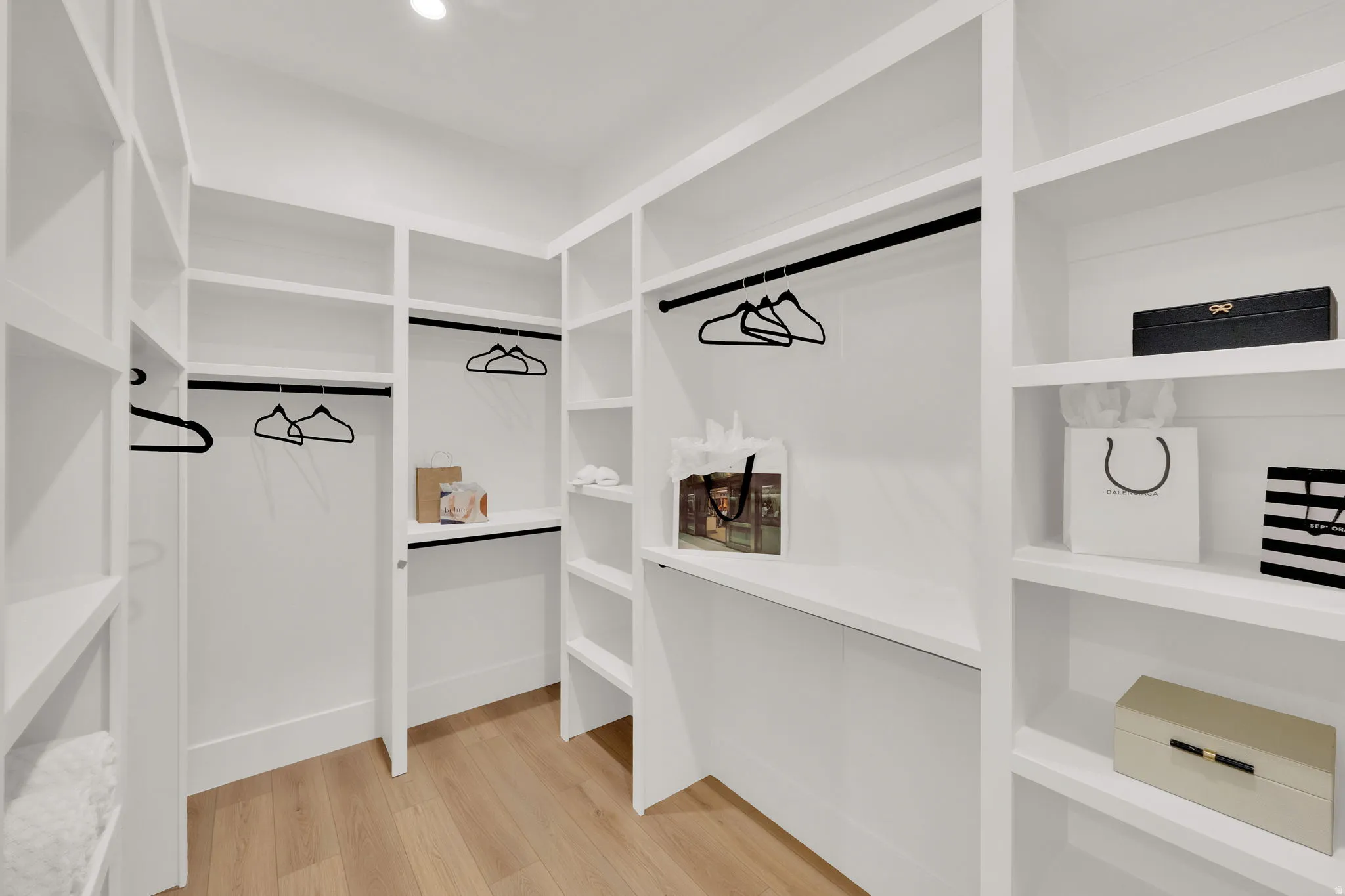 Custom-designed closet system featuring extensive shelving, multiple hanging rods, and wood-finish flooring