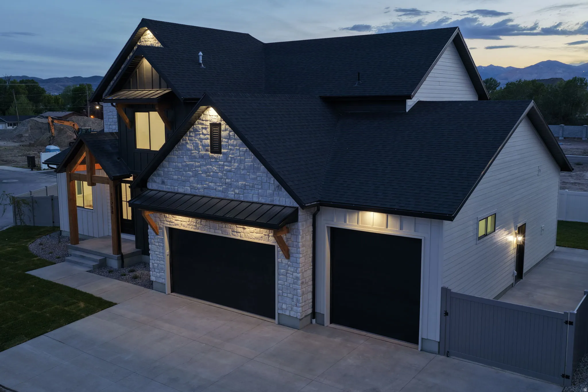Contemporary exterior featuring a multi-gabled roofline and a combination of light-colored stone veneer and vertical siding