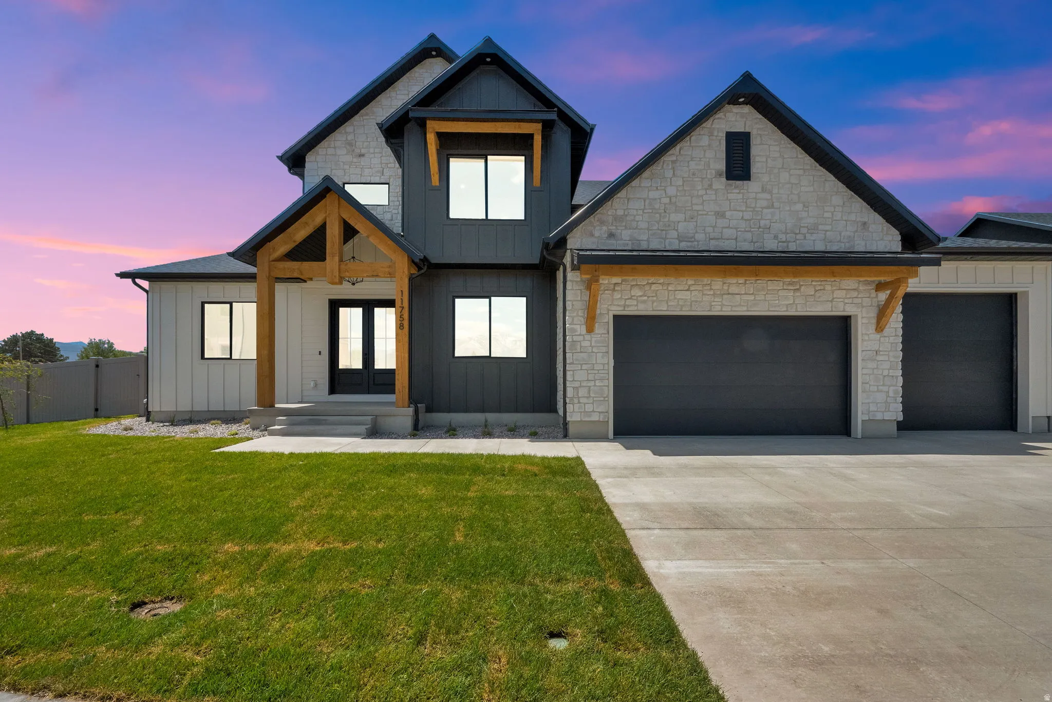 Modern exterior featuring a prominent gabled roofline, stone veneer accents, and dark panel siding