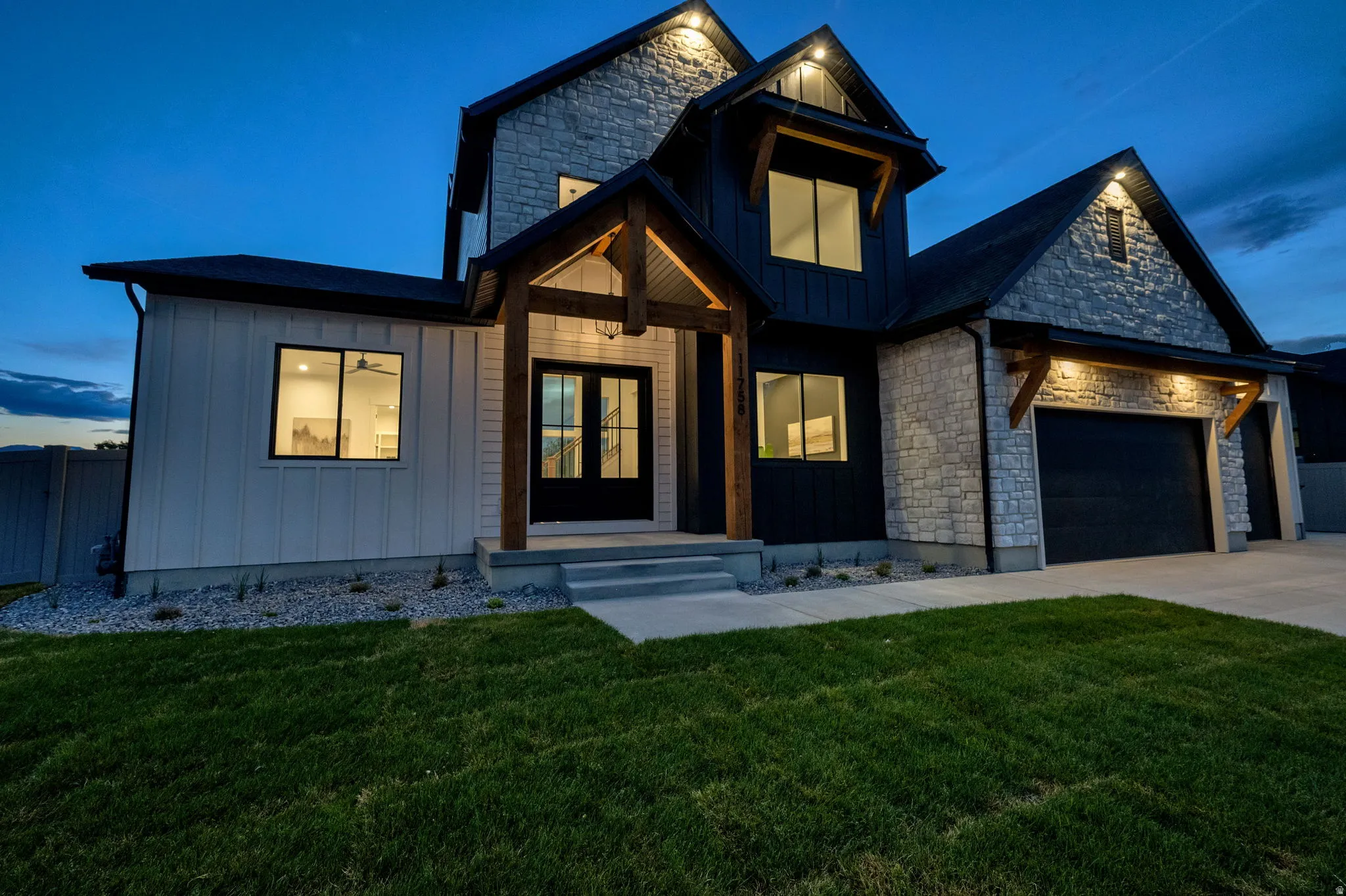 Modern exterior featuring a prominent stone facade, black vertical siding, and white board and batten accents