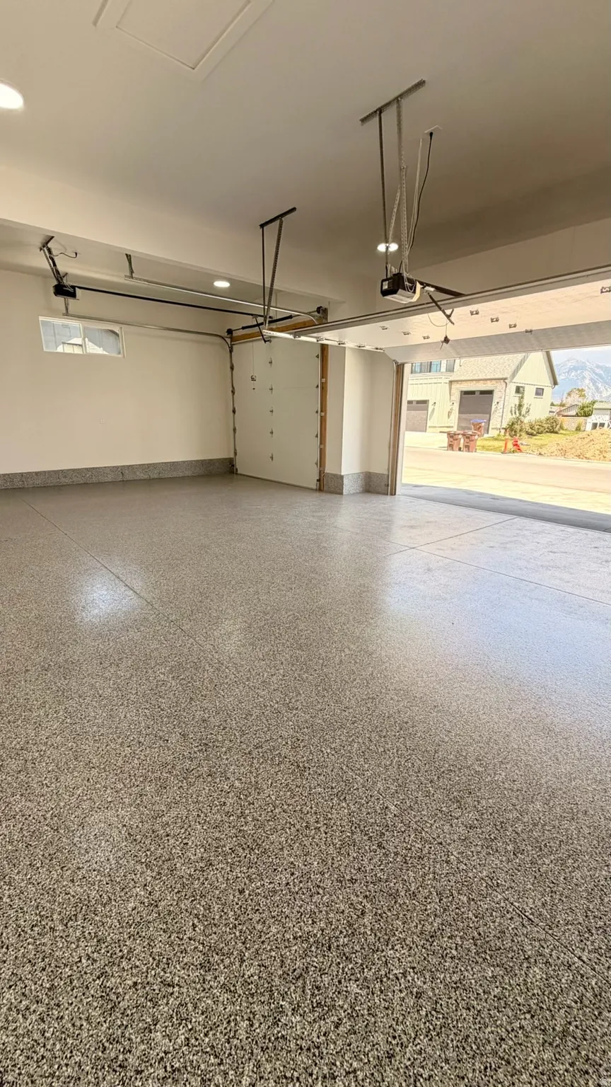 Spacious garage featuring a speckled epoxy flooring, two automatic garage door openers, and recessed ceiling lighting