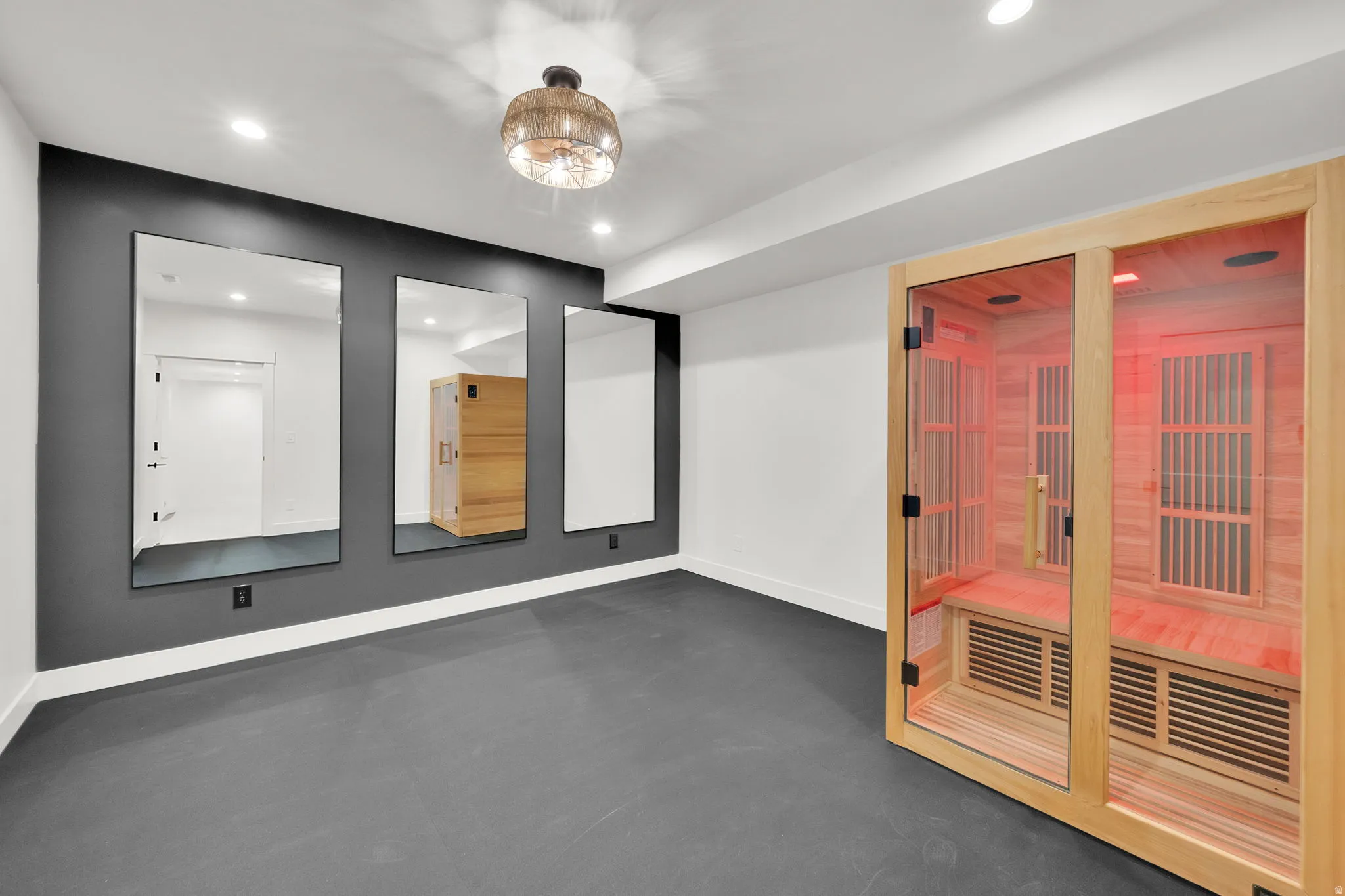 Dedicated fitness room featuring a built-in wood sauna with glass doors, recessed lighting, and a decorative ceiling fixture