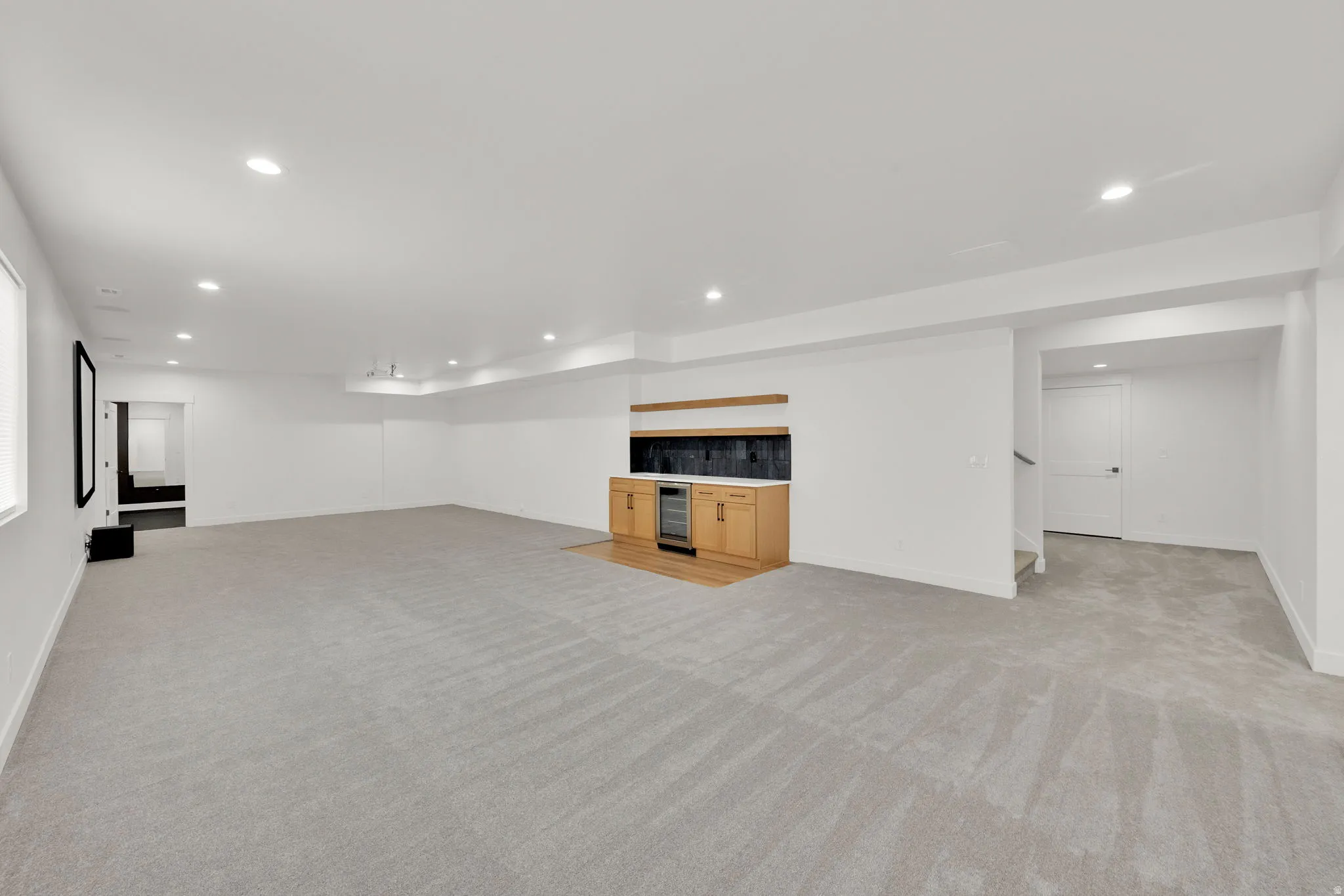 Spacious recreation room featuring light gray carpeting and recessed lighting