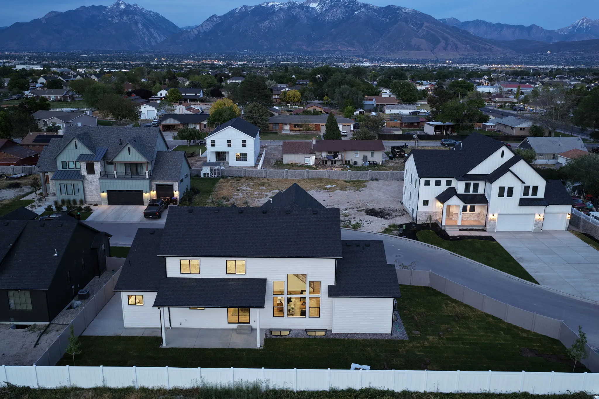 Modern construction featuring a white exterior with black trim, dark shingle roof, and an expansive window wall