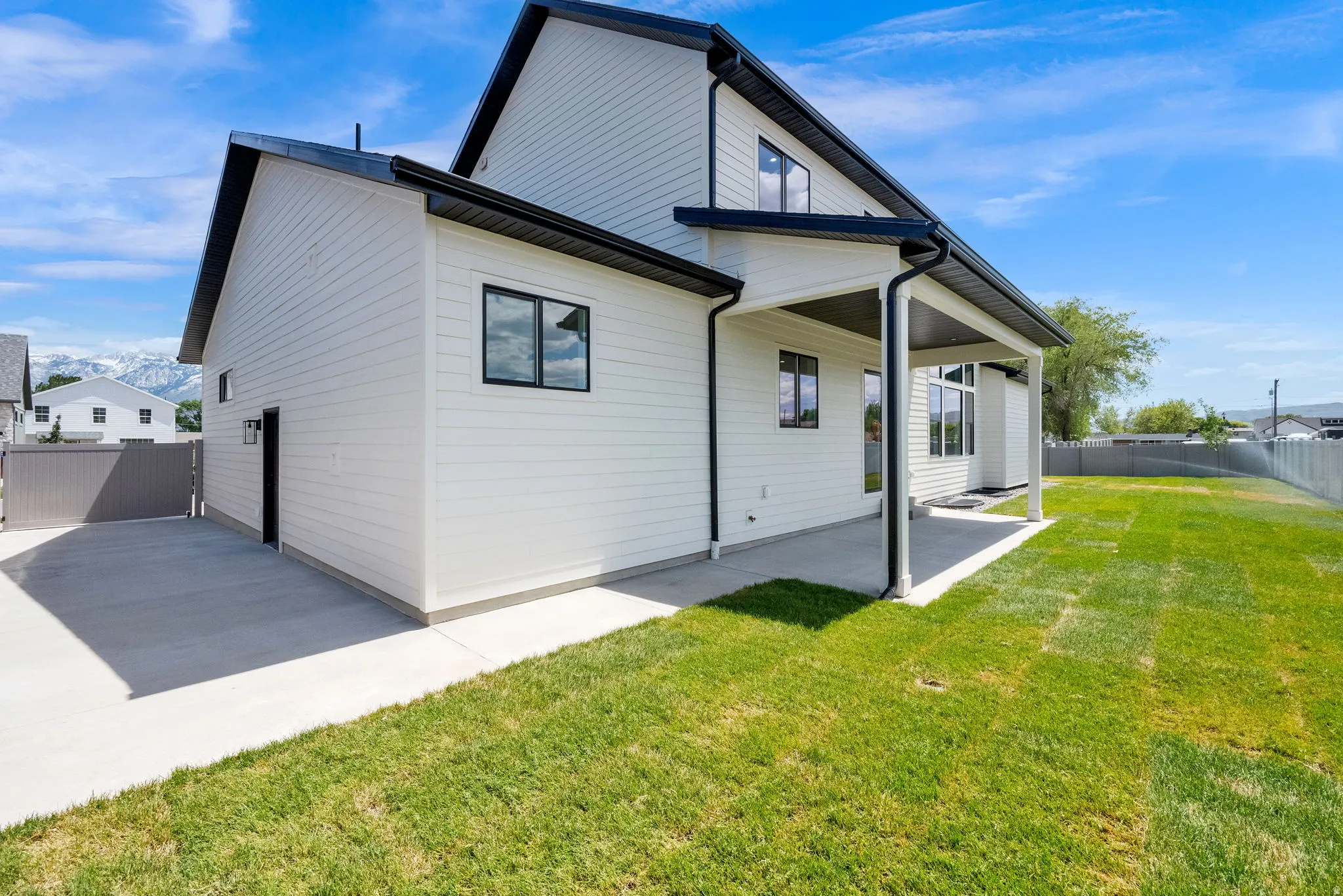 Modern exterior featuring white siding, black-framed windows, and a covered patio
