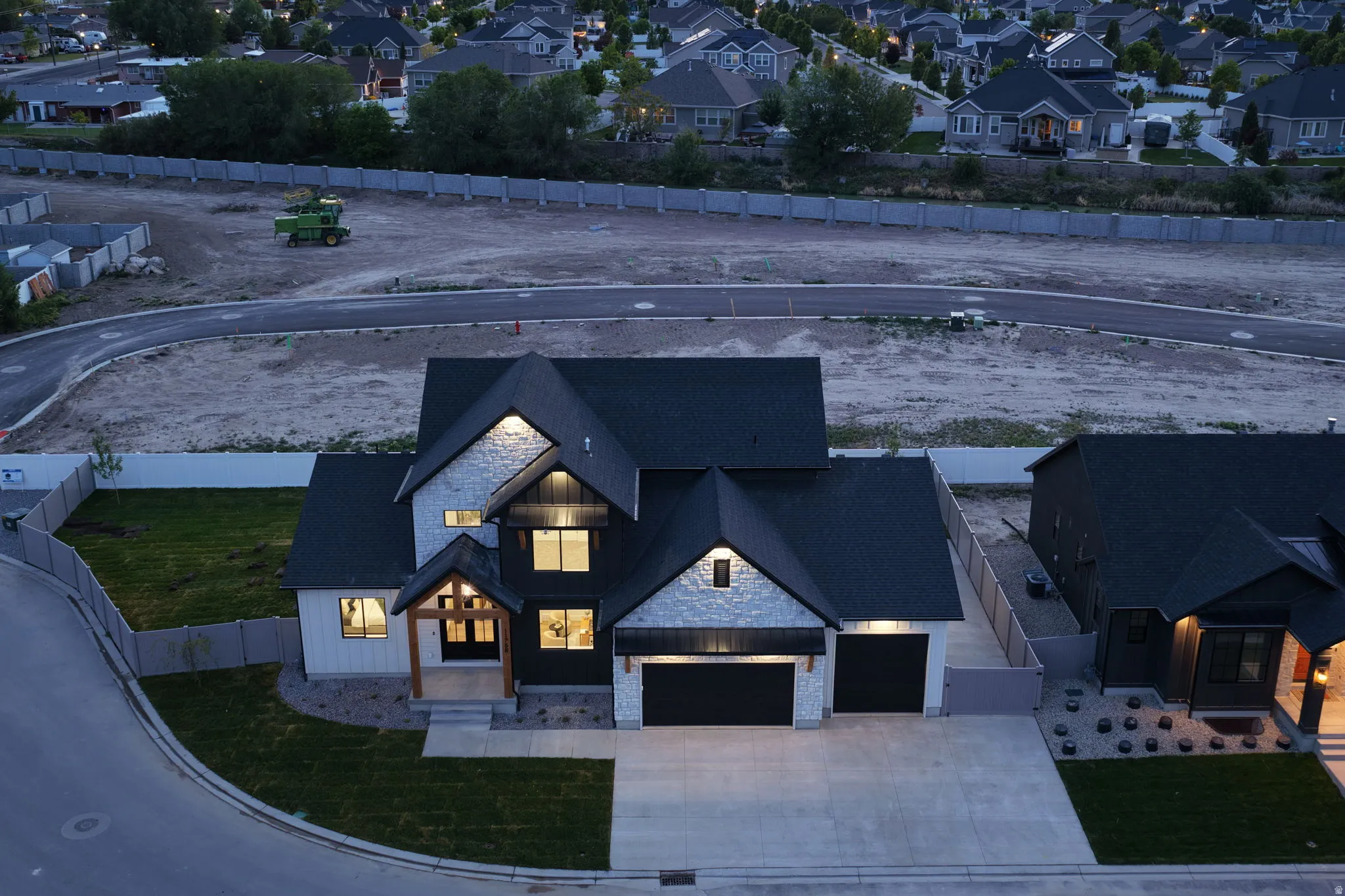 Modern farmhouse exterior featuring a dark asphalt shingle roof, light-colored stone accents, and contrasting dark and white siding