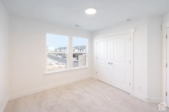 Recessed lighting, light gray carpeting, double window with white trim, white paneled double doors, and a white interior door